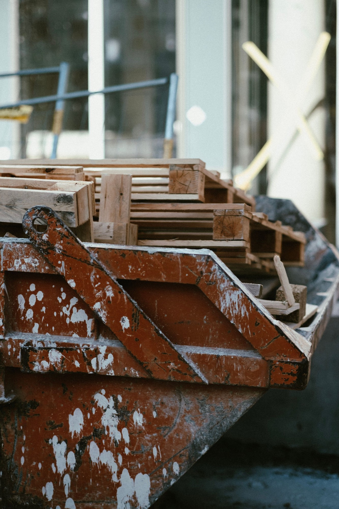 Benne de chantier métallique remplie de palettes et déchets de bois